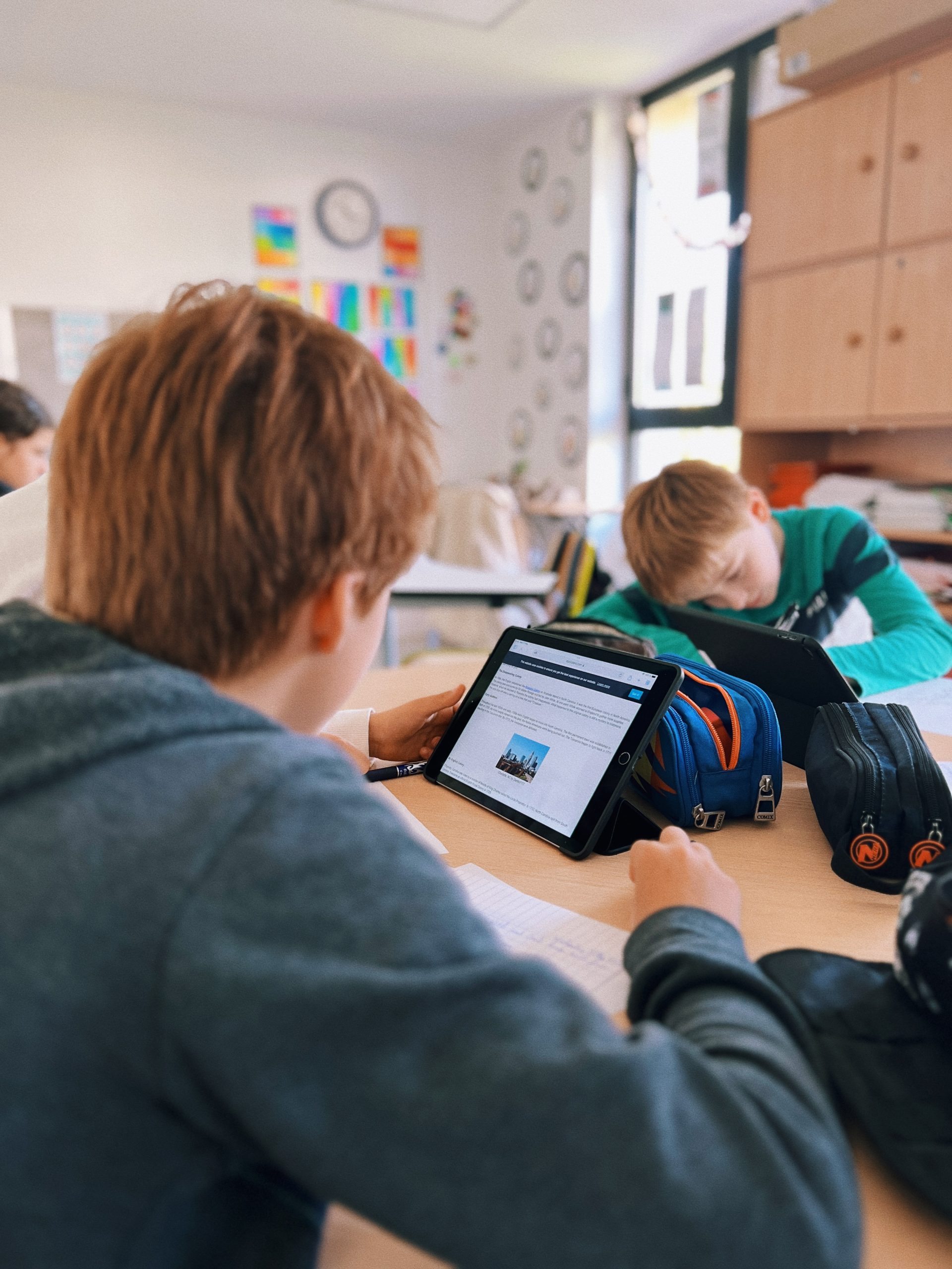 two students doing research on iPads in classroom workgroups