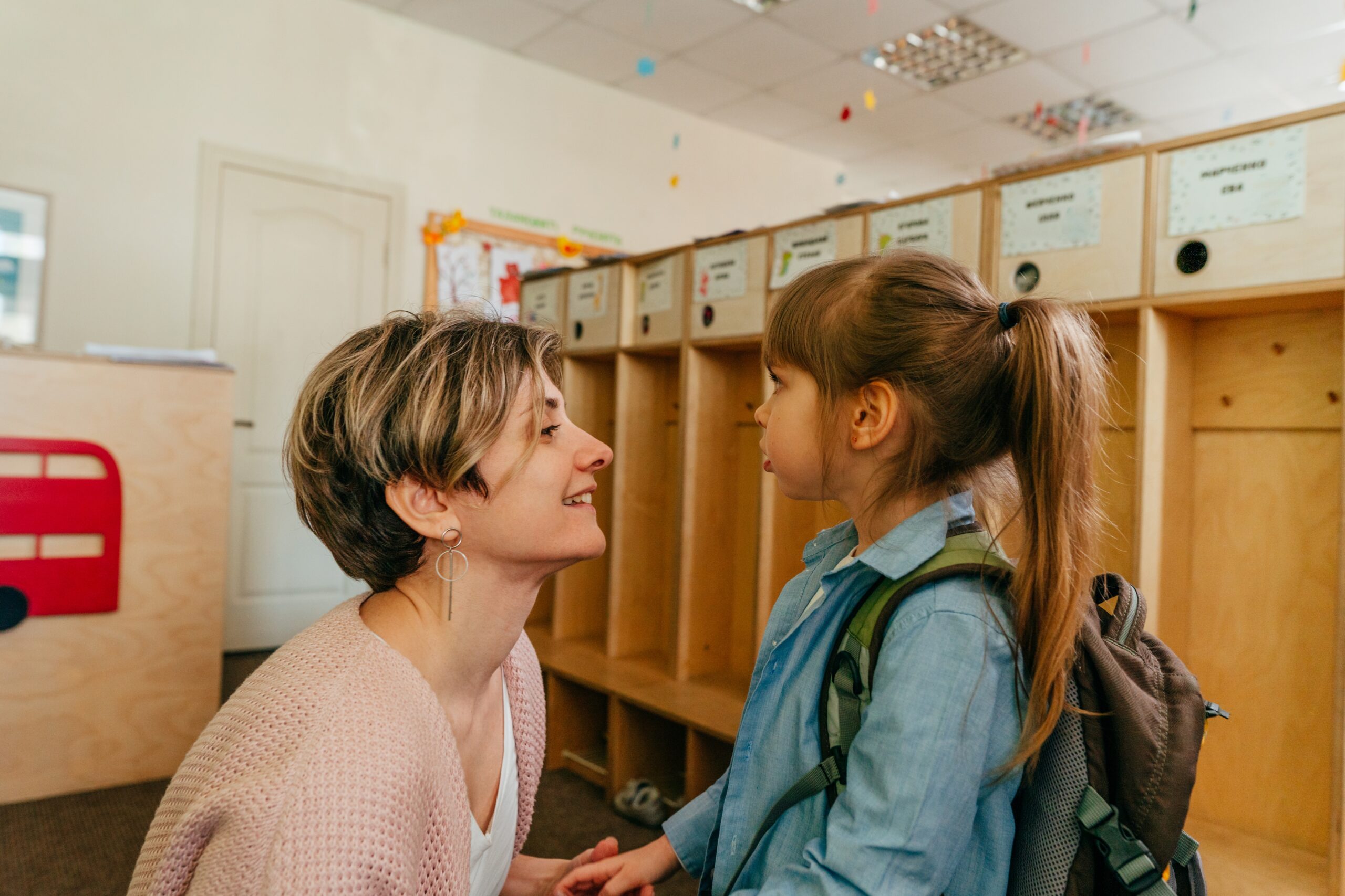 First day at school or kindergarten. Mother with her daughter elementary student standing near the wardrobe at school. Back to school concept.